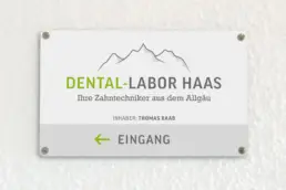 Firmenschild auf weißer Wand