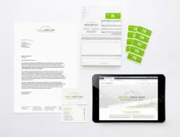 Collage aus Briefbogen, Visitenkarten, Formularblock und Tablet mit Website-Ansicht