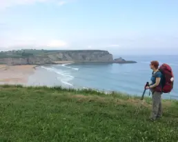 Inhaberin Britta Raab mit Rucksack mit Blick auf die nordspanische Küste auf dem Jakobsweg