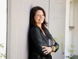 Netzwerkpartnerin Alexandra Lachner lehnt lächelnd an einer Wand