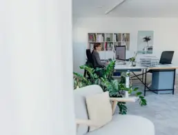 Blick auf zwei Schreibtische und Regal dahinter, Britta Raab arbeitet am linken Schreibtisch