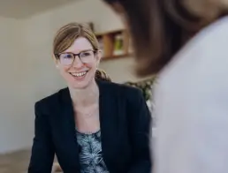 Inhaberin Britta Raab lächelnd im Gespräch mit Kundin, die im Anschnitt unscharf und von hinten zu sehen ist