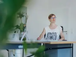 Inhaberin Britta Raab sitzt am Schreibtisch und blickt nachdenklich zur Seite