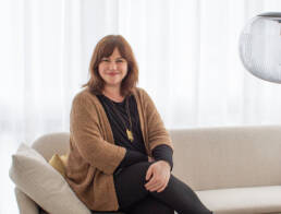 Netzwerkpartnerin Alexandra Keßler sitzt lächelnd auf dem Sofa